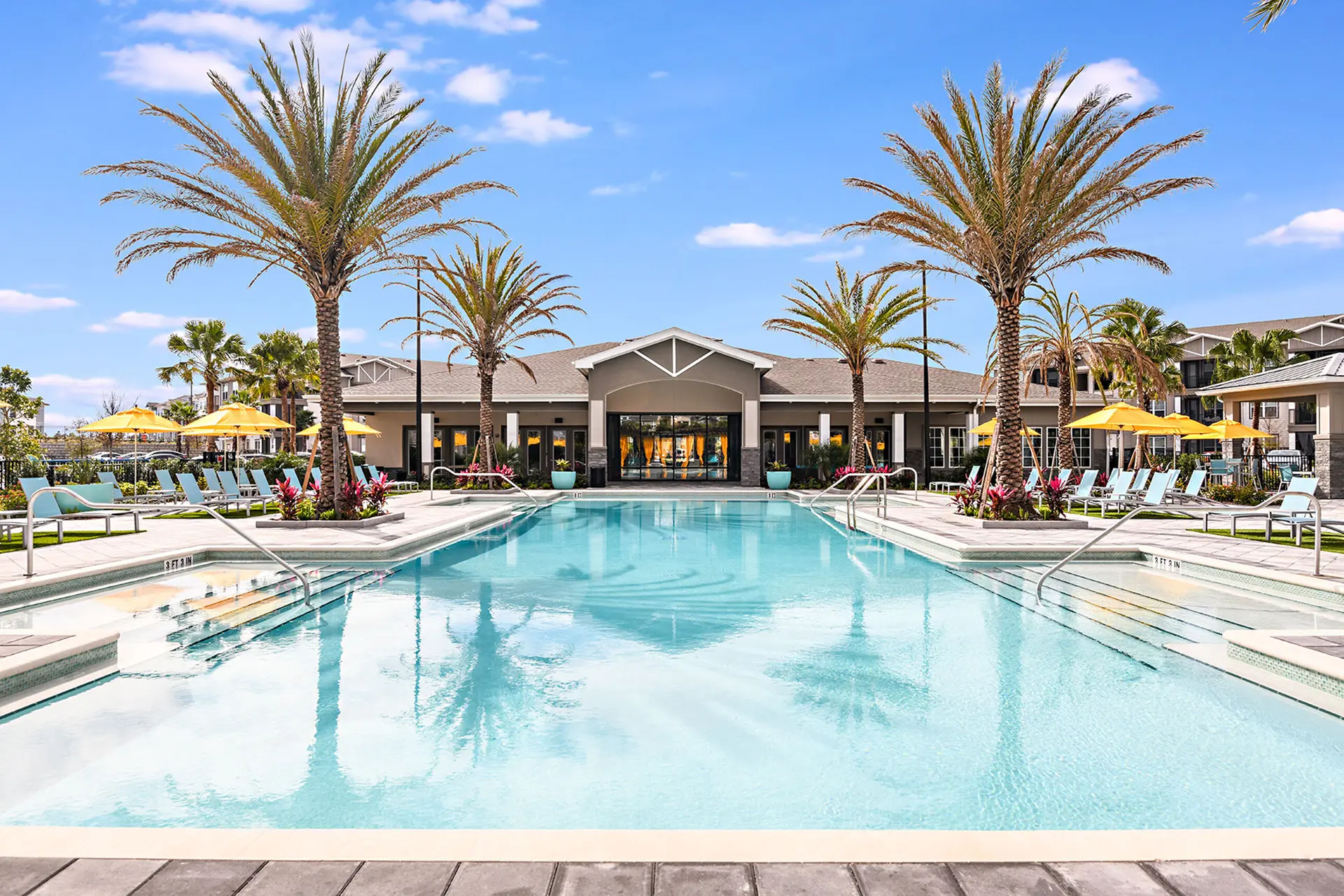 large apartment swimming pool with four sets of entry stairs and palm trees