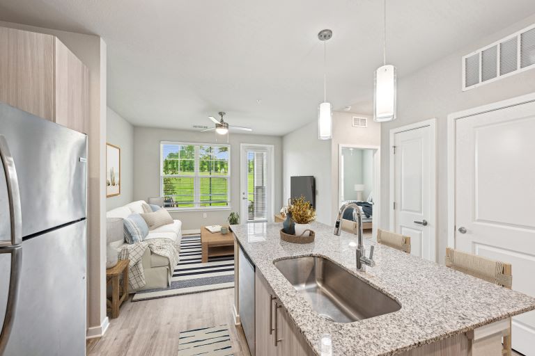 Renovated open space kitchen with stainless steel appliancesm granite counters, island, modern pendant lighting, living room with ceiling fan,