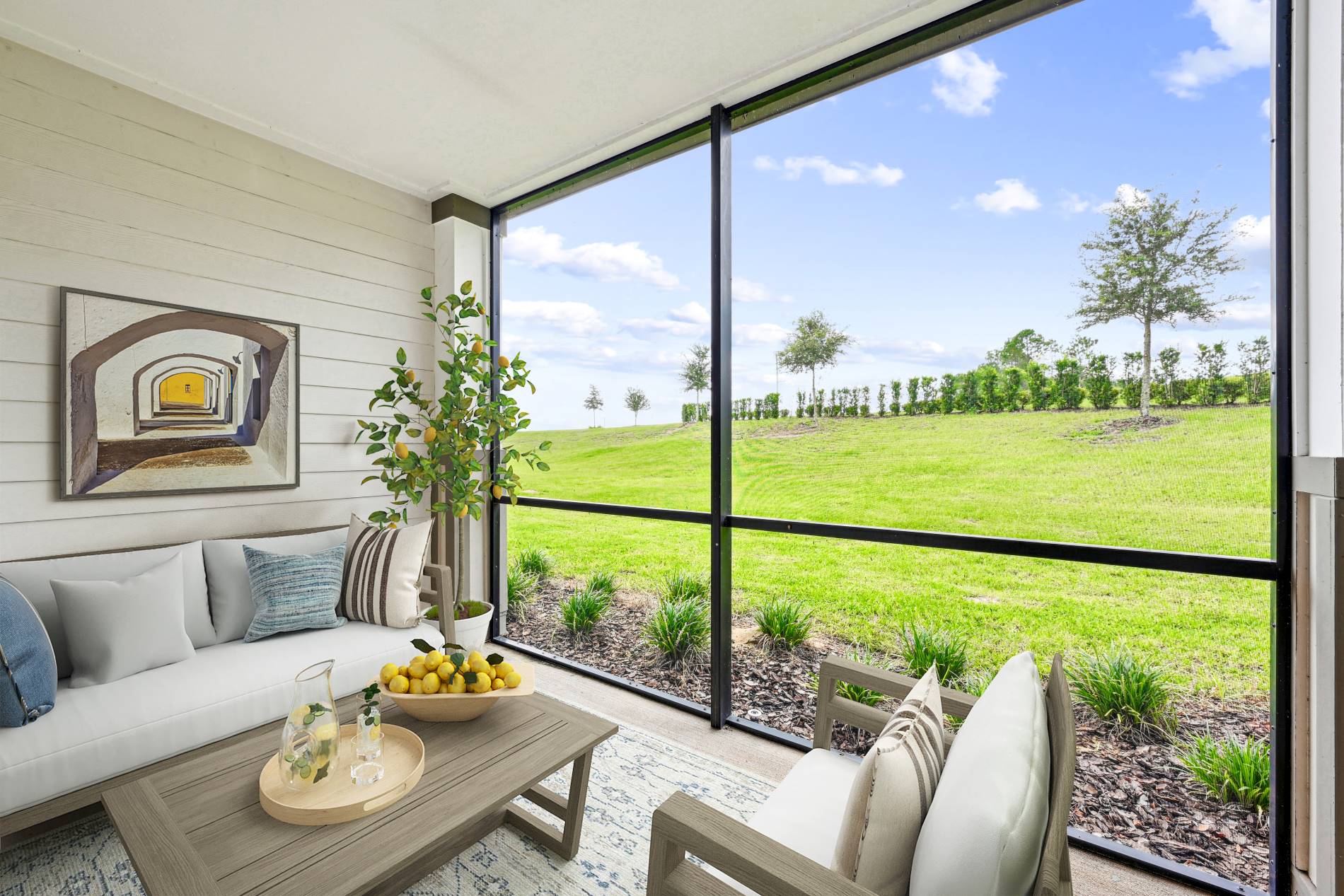 Enclosed screened in patio with view of greenery, wood and beige porch furniture, paneled wall with wall art